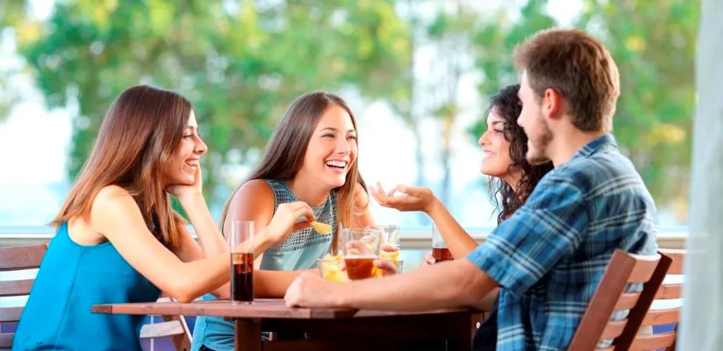 Group of friends talking and drinking beer at a table and eating chips